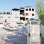 Sistema di microirrigazione t.b.t. su una terrazza sul tetto con una donna su una sedia a sdraio sullo sfondo.
