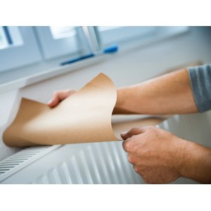 Uomo che copre il radiatore con carta protettiva marrone LUX.