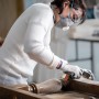Donna che leviga il legno con spugna abrasiva Bosch Expert. Abrasivi per legno e vernice.