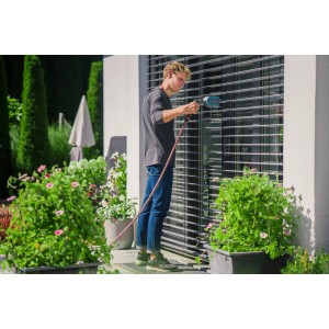 Uomo pulisce le persiane con la spazzola per persiane Gardena Cleansystem con attacco acqua.