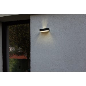Lampada da parete solare a LED Lutec Fadi nera con sensore di movimento su muro grigio.