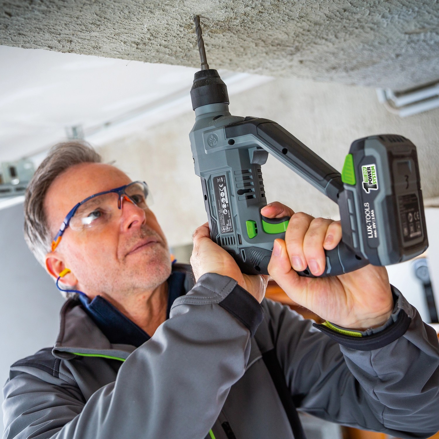 Uomo fora il soffitto con il trapano a percussione a batteria LUX A-BH-20.