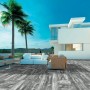 Terrazza con pavimentazione per esterni t.b.t. grigia e mobili da giardino bianchi davanti a una casa moderna.