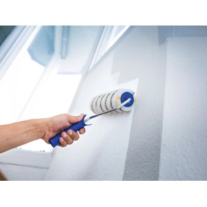 Rullo per pittura LUX da 25 cm mentre dipinge una parete. Rullo con manico blu e rivestimento a righe oro-grigio.