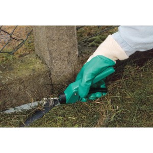 Mano con guanto in nitrile da giardino LUX S che taglia l'erba. Abbigliamento da giardino per un lavoro sicuro.