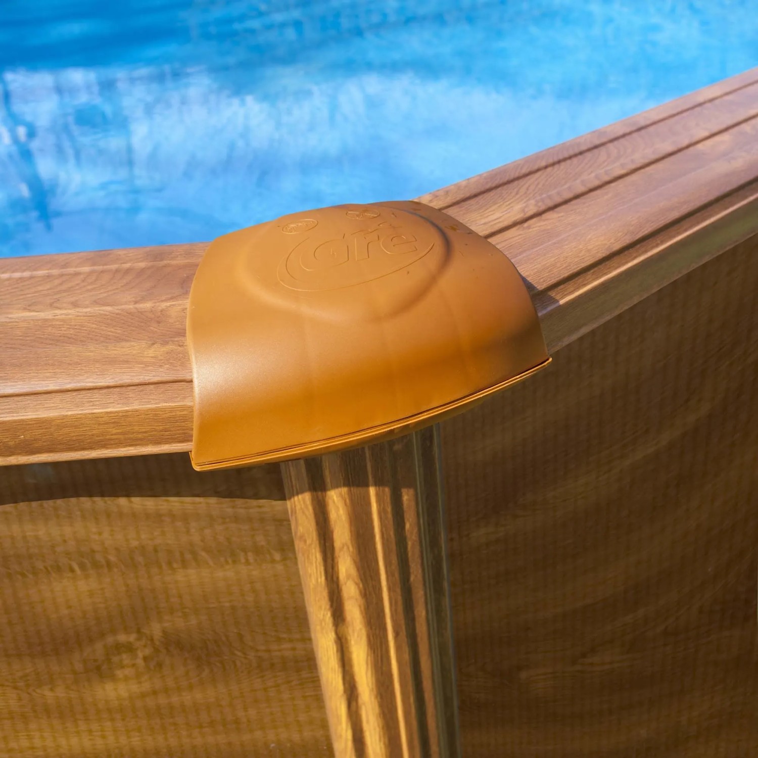 Piscina Gre Mauritius Ovale: parete effetto legno, tappo angolare marrone con logo Gre, acqua blu.