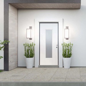 Porta blindata bianca con inserto in vetro e due luci esterne affiancata da piante in vasi bianchi.