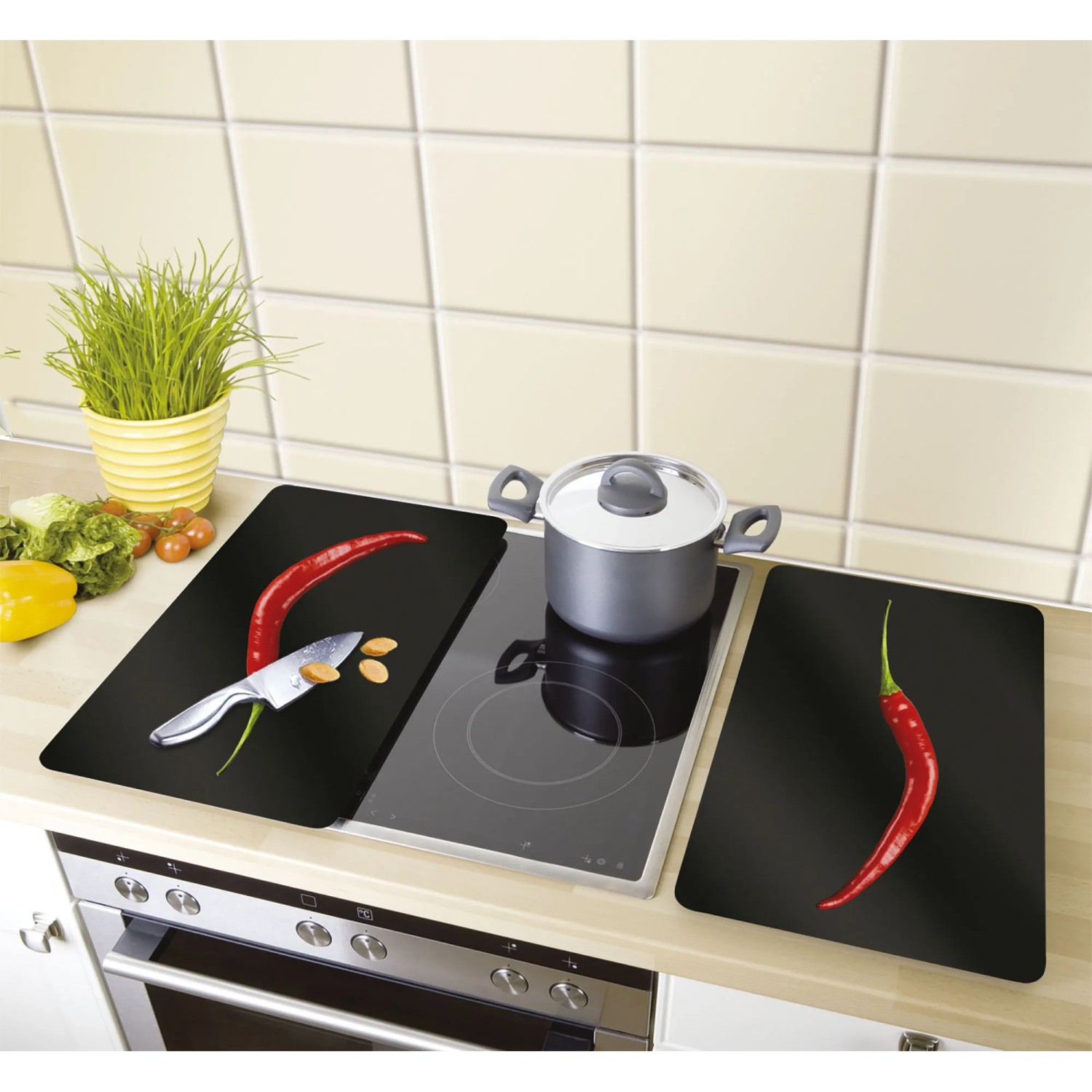 Coprifornelli Wenko Hot Peperoni, set da 2, su piano cottura con pentola e ingredienti.