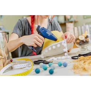 Donna usa pistola per colla a caldo blu per il fai da te. Pistola incollatrici.