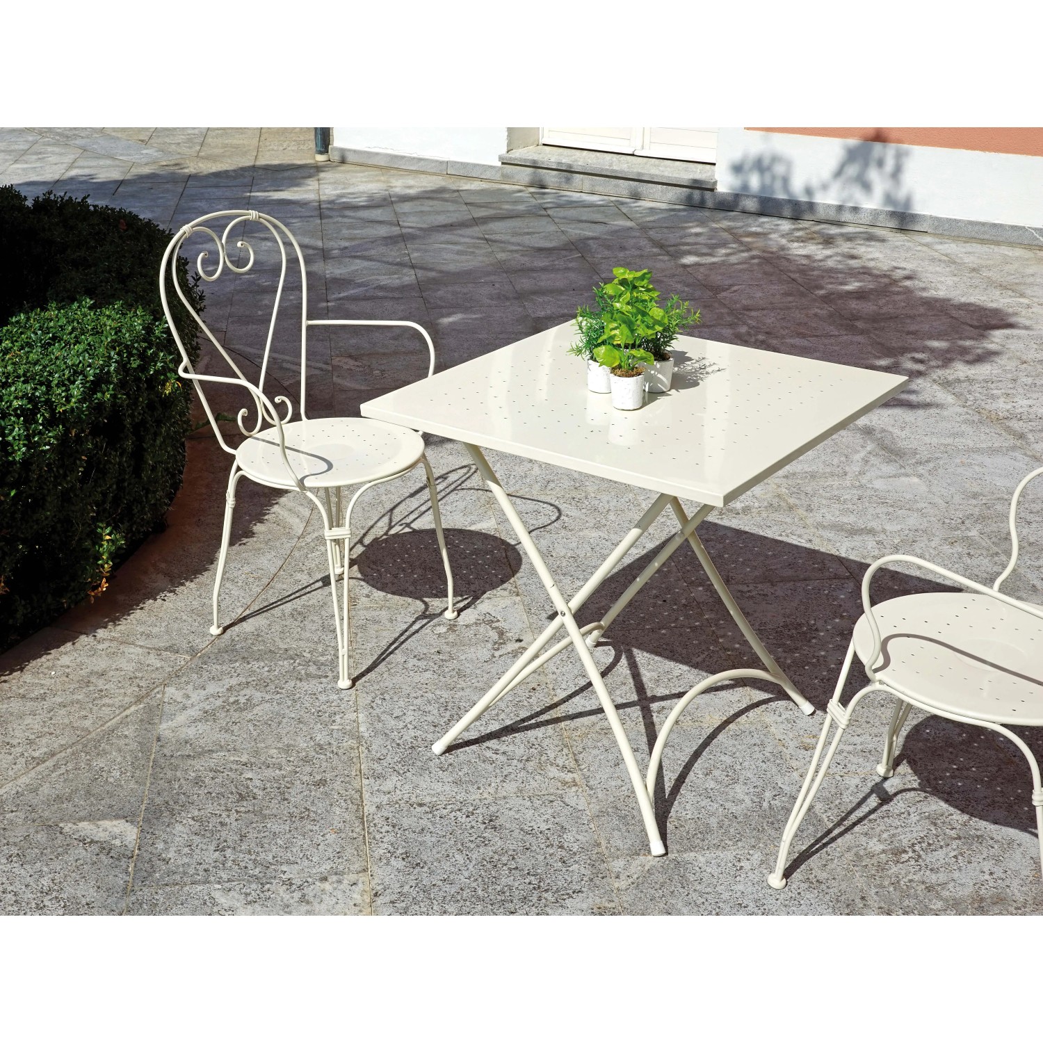 Tavolo da giardino quadrato beige con due sedie in metallo.
