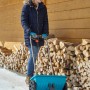 Donna che usa lo spargitore Gardena L in inverno per spargere sulla neve.