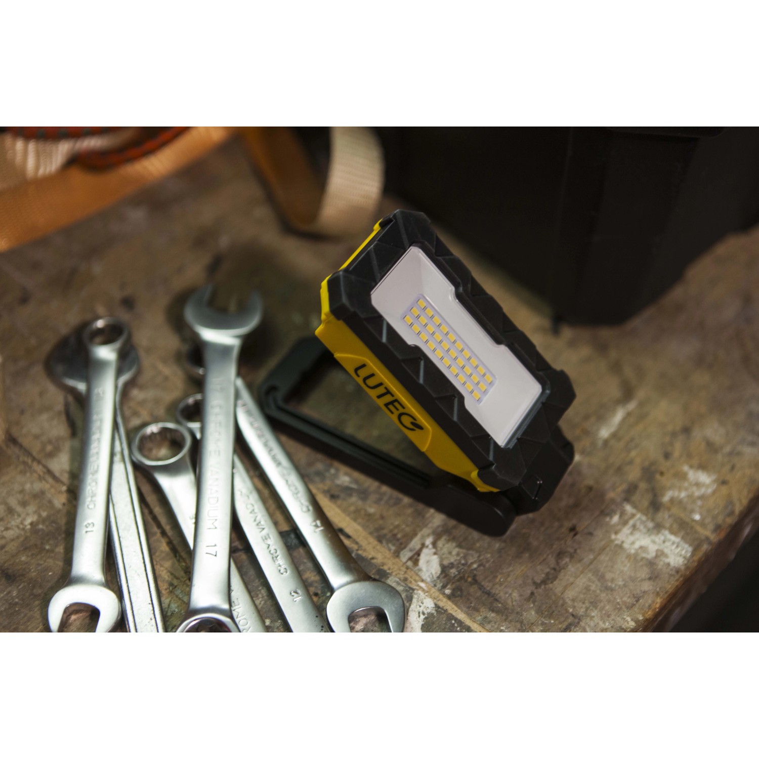 Faro LED da esterno giallo t.b.t. con attrezzi su un banco da lavoro.