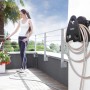 Avvolgitubo a parete con tubo da giardino in uso su terrazza.