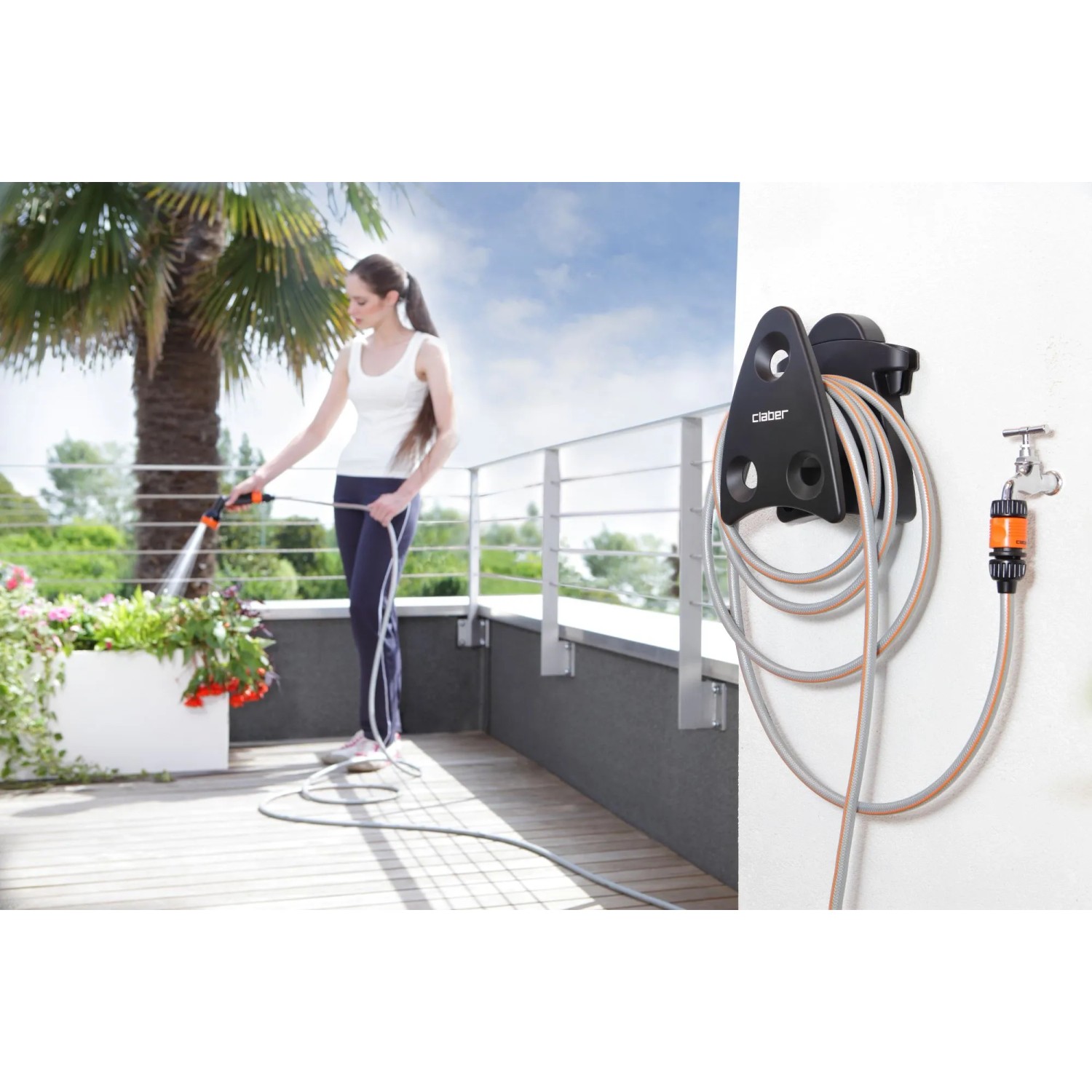 Avvolgitubo a parete con tubo da giardino in uso su terrazza.