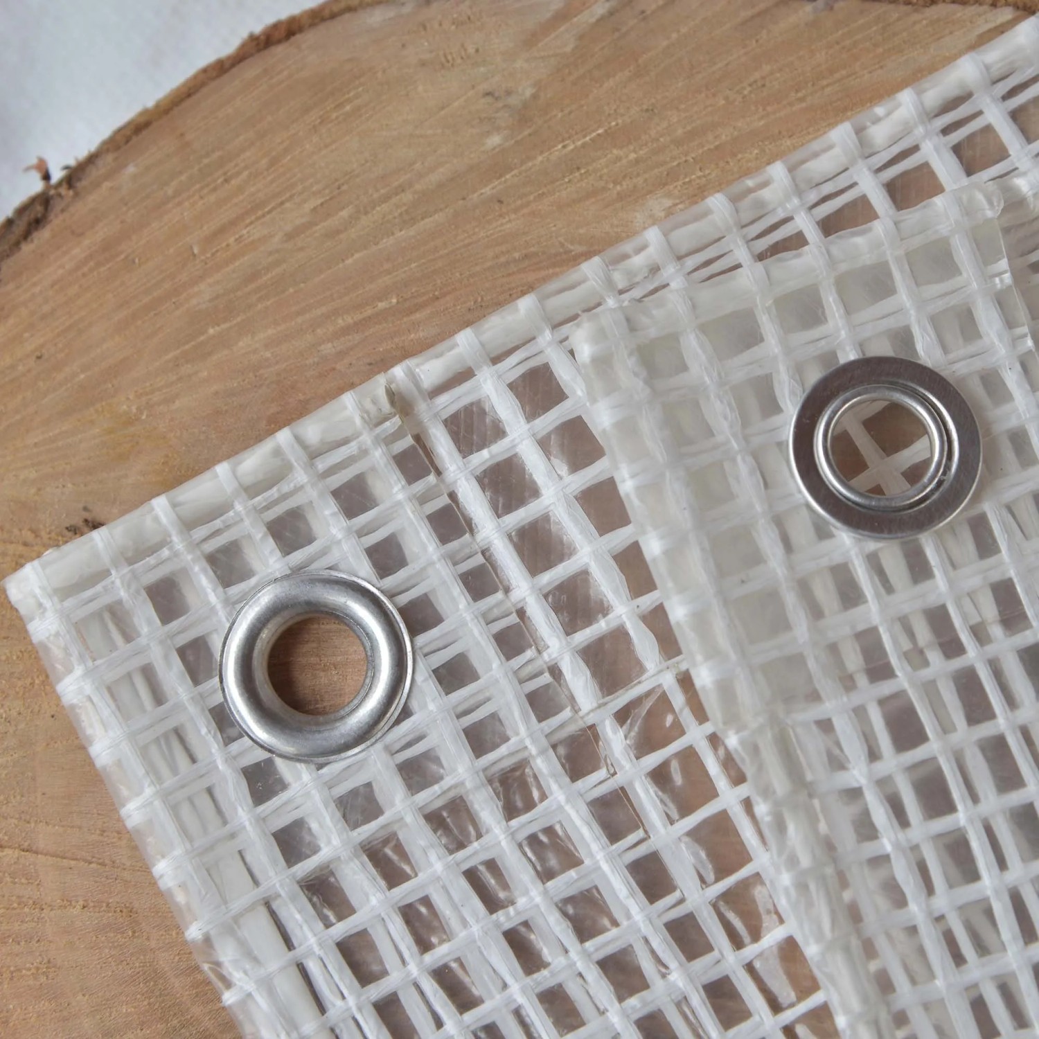 Telone di copertura trasparente con occhielli, ideale per la protezione in giardino o in cantiere.