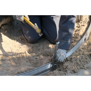 Installazione di un bordo giardino t.b.t. con martello e picchetto nel giardino.