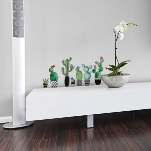 Adesivi murali cactus in vaso come decorazione su comò bianco accanto a orchidea.