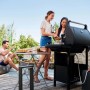 Scena con barbecue a gas t.b.t. che griglia all'aperto con amici.
