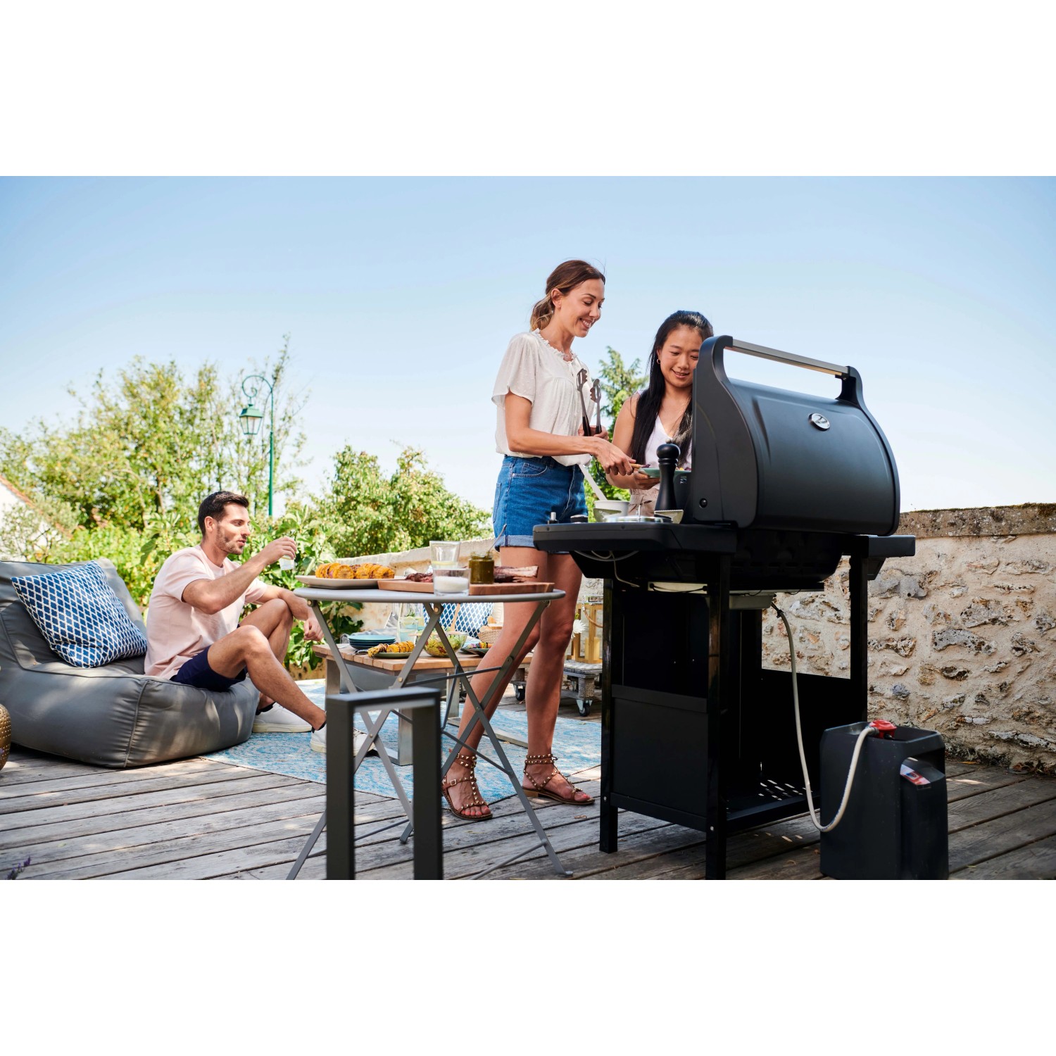 Scena con barbecue a gas t.b.t. che griglia all'aperto con amici.