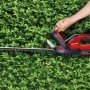 Tagliasiepi a batteria Einhell GC-CH 1855/1 Li Kit rosso-nero durante il taglio di una siepe.