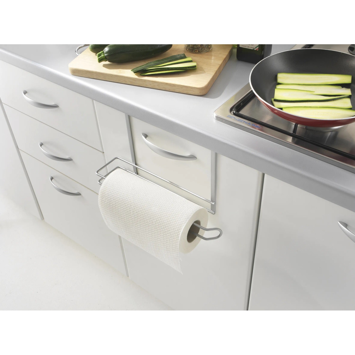 Porta rotolo da cucina in metallo su anta bianca. Utensili da cucina sullo sfondo.