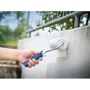 Rullo per verniciatura grigio LUX PRO (Ø 8 cm x 18 cm) in uso, mentre dipinge un muro.