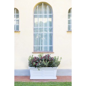 Fioriera da esterno t.b.t. bianca con piante davanti a un muro di casa.