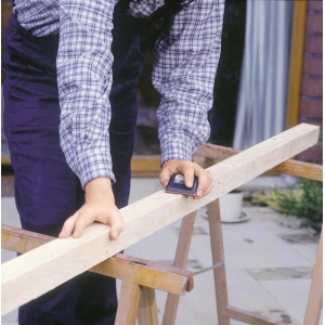 Artigiano che leviga il legno con blocco abrasivo manuale LUX 70x130 mm per risultati precisi.