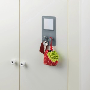 Appendiabiti da parete grigio con specchio e ganci, con chiavi e una piccola borsa appesa.