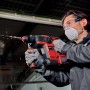 Martello perforatore rosso in azione mentre fora un muro. Strumento per lavori di foratura.