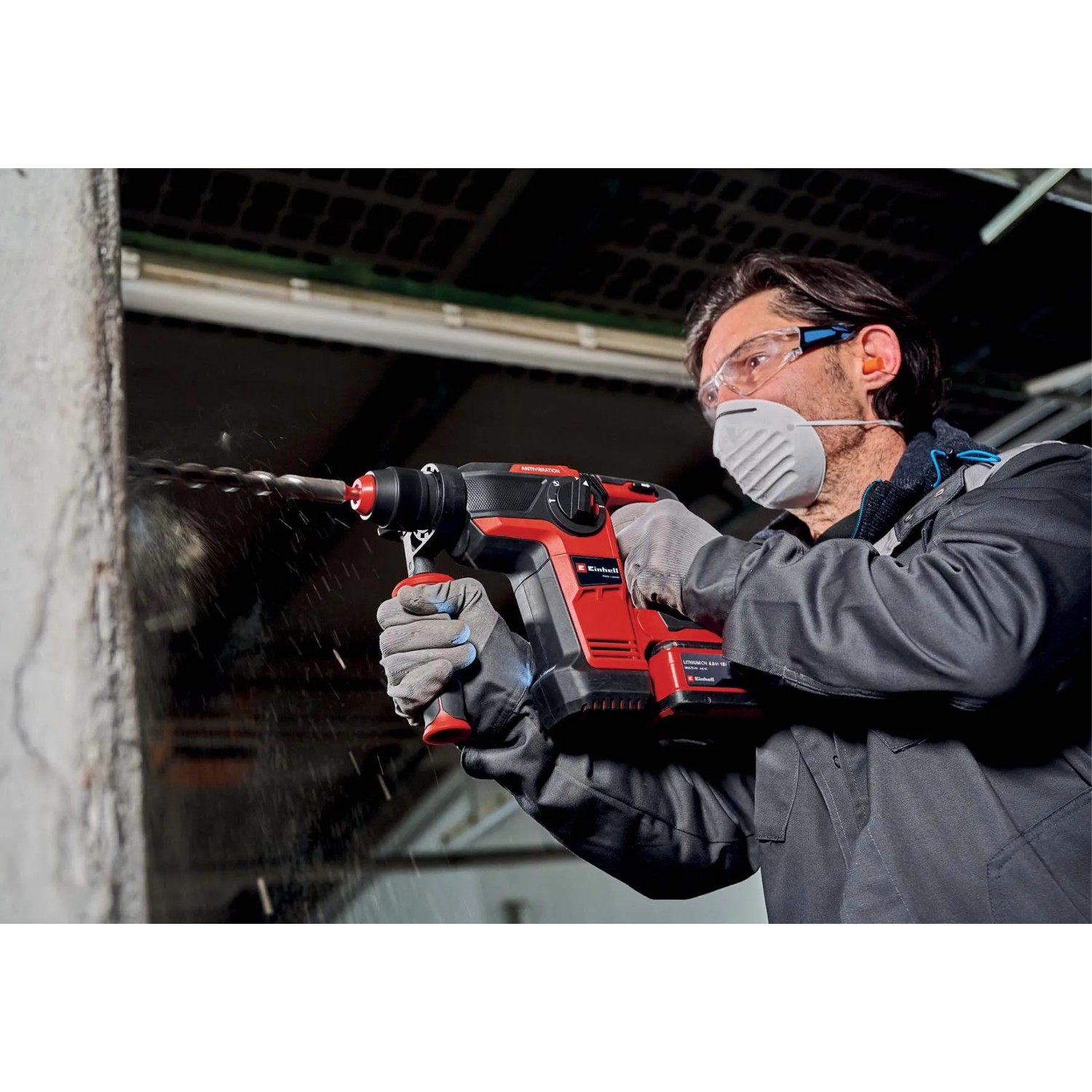 Martello perforatore rosso in azione mentre fora un muro. Strumento per lavori di foratura.