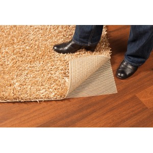 Sottotappeto OBI (80x130cm) sotto tappeto beige su pavimento in legno, con piede