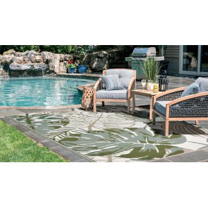 Tappeto da esterno con motivo a foglie su patio con mobili da giardino e piscina.