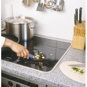 Raschietto universale LUX in uso su un piano cottura in vetroceramica per rimuovere residui di cibo.