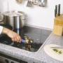 Raschietto universale LUX in uso su un piano cottura in vetroceramica per rimuovere residui di cibo.