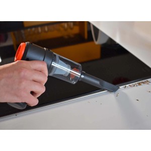 Aspirapolvere a batteria in azione: mano tiene t.b.t. nero su una superficie per aspirare briciole.