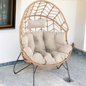 Poltrona da esterno in vimini con cuscini beige, ideale per patio e giardino.