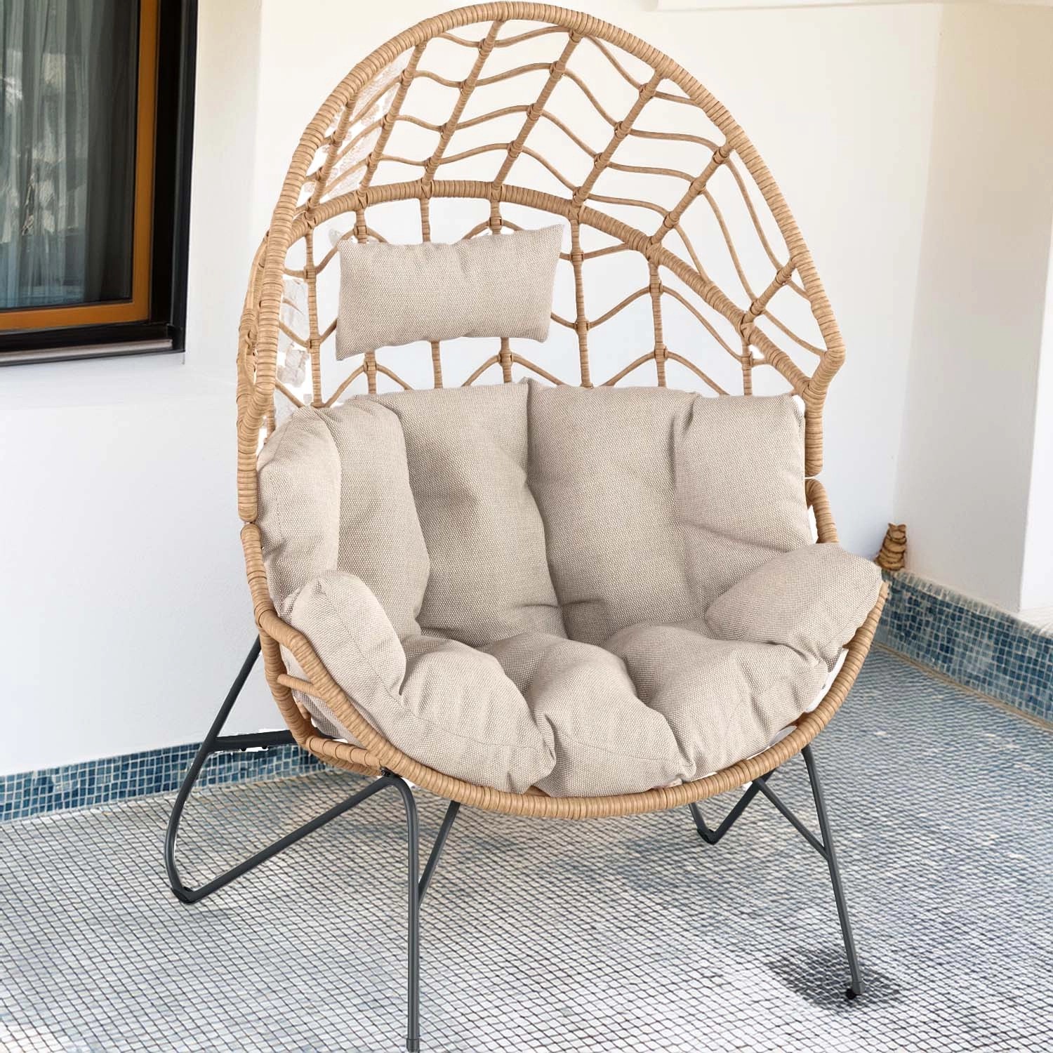 Poltrona da esterno in vimini con cuscini beige, ideale per patio e giardino.