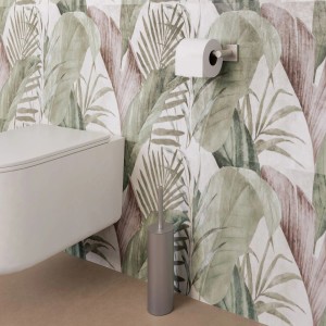 WC sospeso, porta carta igienica e scopino davanti a parete con motivo a foglie.