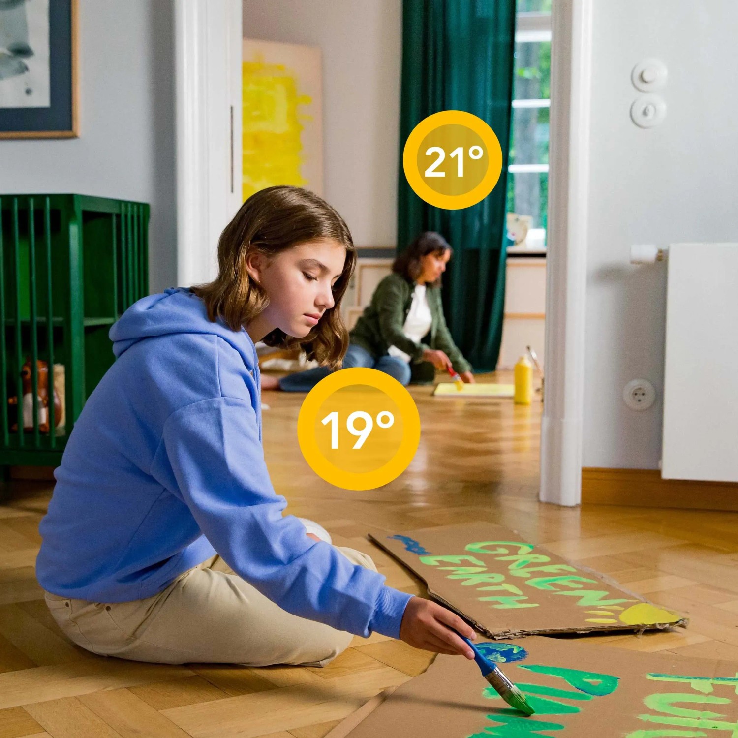 Due bambini dipingono poster in una stanza con termostato per radiatori tado° per il controllo individuale della stanza.