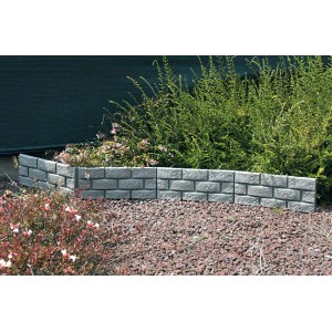 Muretto/bordura da giardino t.b.t. grigio effetto pietra, circonda un'aiuola con piante.