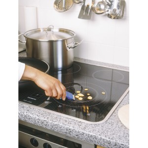 Raschietto universale LUX in uso per pulire residui di cibo da un piano cottura in vetroceramica.