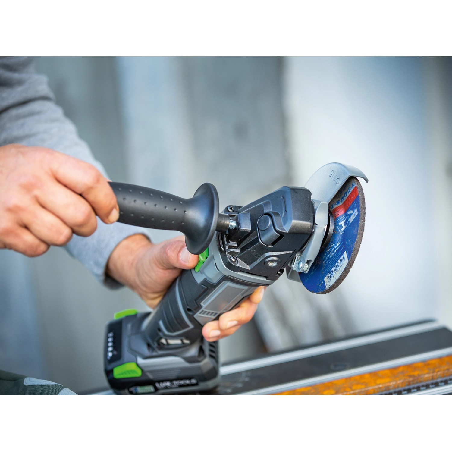 Smerigliatrice angolare a batteria LUX A-WS-20/115 con impugnatura ausiliaria e disco abrasivo. Utensile a batteria per lavori di smerigliatura.