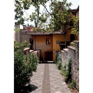 Pavimento in pietra in stile mediterraneo, circondato da piante e muri.