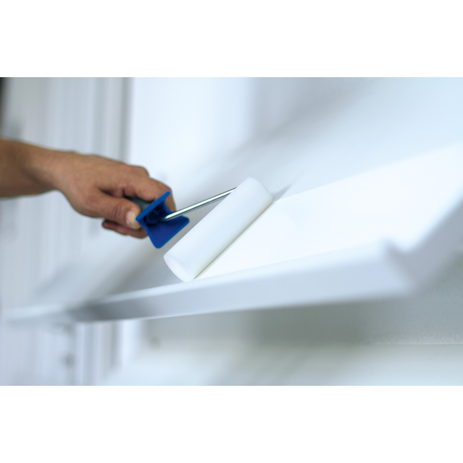 Rullo per pittura LUX con rullo in schiuma e impugnatura morbida blu-nera durante la verniciatura.