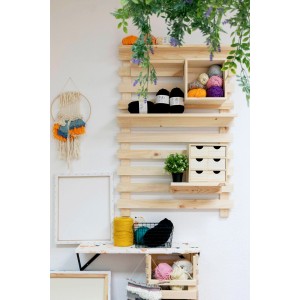 Mensola in legno con cassettiera t.b.t., filati e decorazioni su una parete.