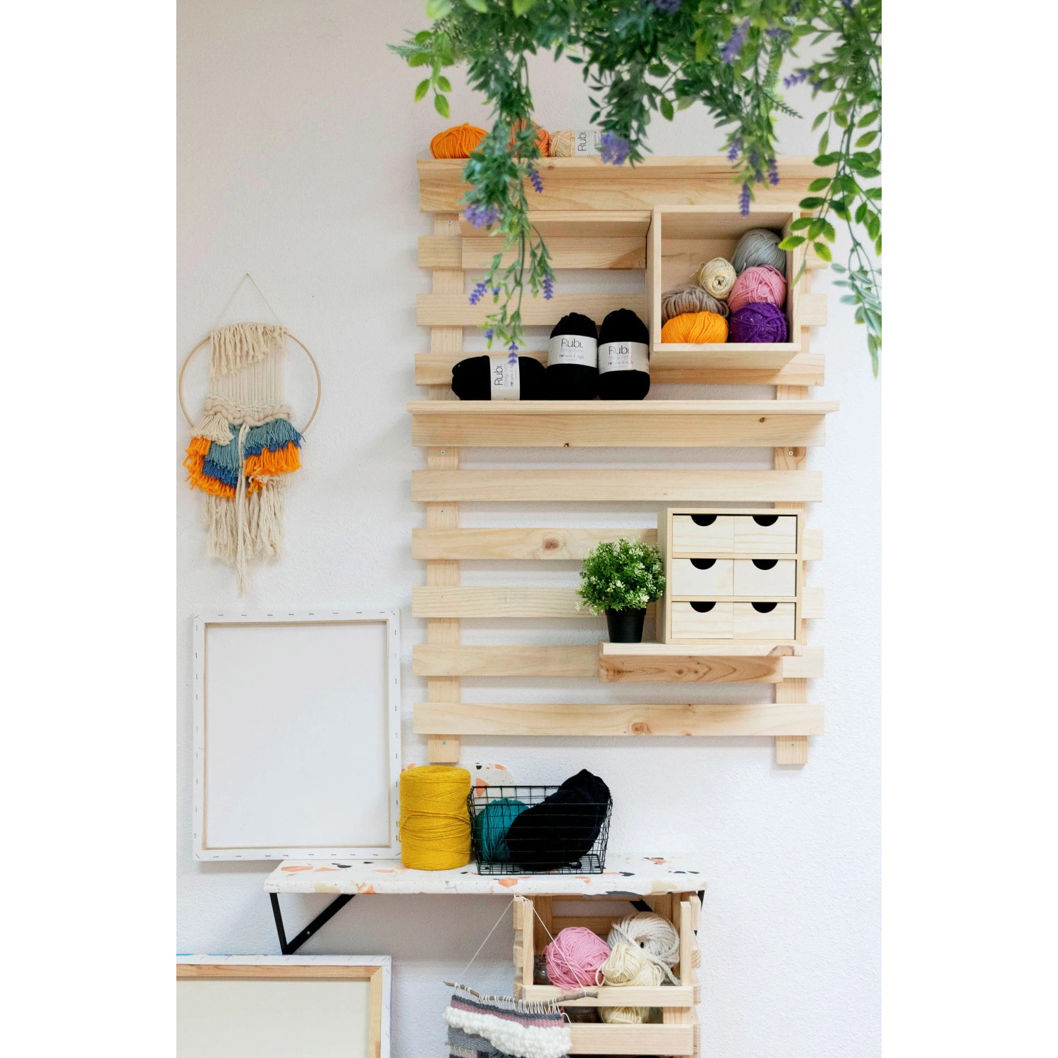 Mensola in legno con cassettiera t.b.t., filati e decorazioni su una parete.