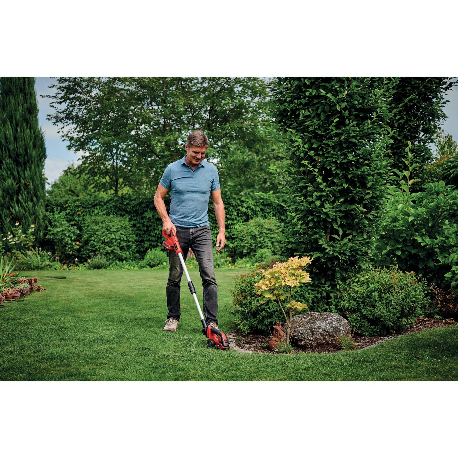 Uomo che utilizza le cesoie a batteria per erba e arbusti Einhell Power X-Change GE-CG 18/100 Li T-Solo in giardino.
