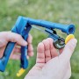 Pinza per recinzioni Rapid FP222 in azione, dettaglio della pinza e di un anello di fissaggio in mano.
