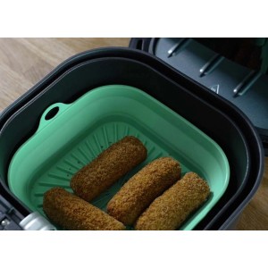 Friggitrice ad aria con contenitore in silicone verde e crocchette. Contenitore per una facile pulizia.